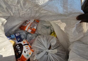 Packed Jan Sewa Trust supplies in white bags, including food items
