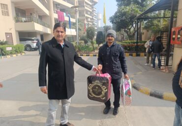 Jan Sewa Trust volunteers handing bags of supplies in front of a building