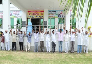Jan Sewa Trust-NGO volunteers raising hands in front of an educational building