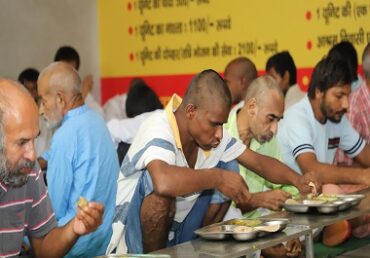 Volunteers from Jan Sewa Trust-NGO serving food to elderly men in a community event