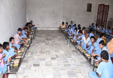 Jan Sewa Trust-NGO students in blue uniforms eating in dining hall