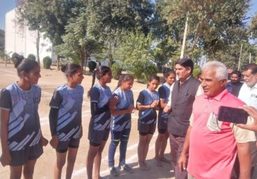 Group of young athletes in matching uniforms with officials on a track